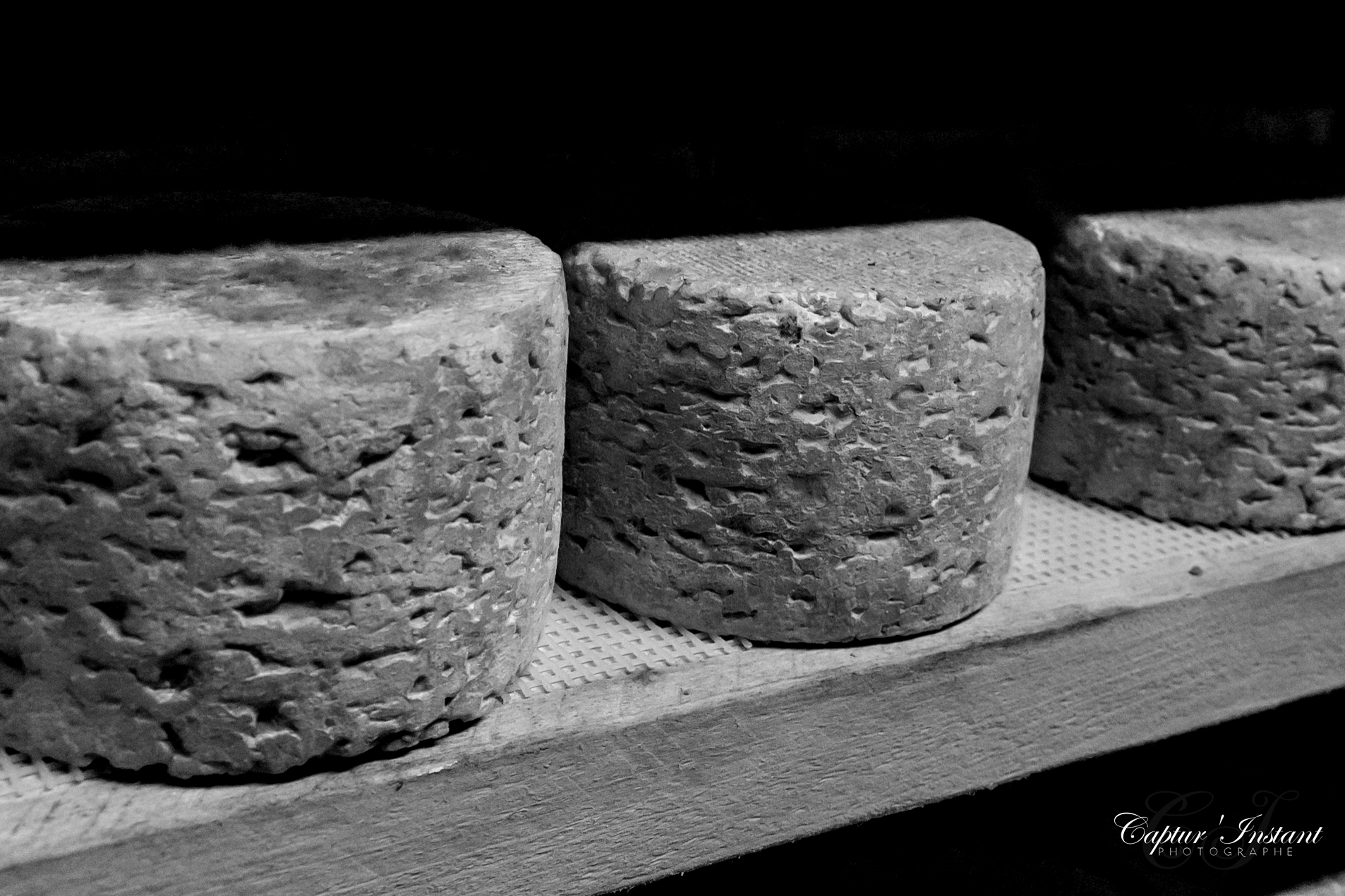 Photo en noir et blanc de formages dans une cave